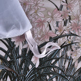 Close-up of fashionable high-end satin duvet cover with pastel plant printing and fabric ties.