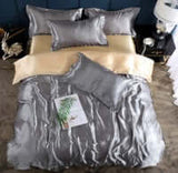 Elegant silver quilt cover set with pillows for a luxurious bedroom décor, featuring smooth silk surface.