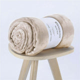 Soft flannel coral fleece nap blanket rolled on a wooden stool, perfect for air conditioning use.