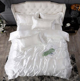 Elegant white silk bed sheet quilt cover with matching pillows in a luxurious bedroom setting.