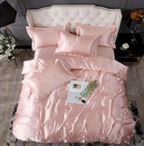 Pink silk bed sheet quilt cover set with decorative pillows for a luxurious sleep experience.