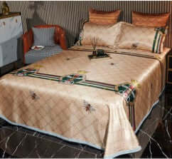 Ice silk three-piece quilt cover set in warm tones with decorative pillows on a stylish bed.