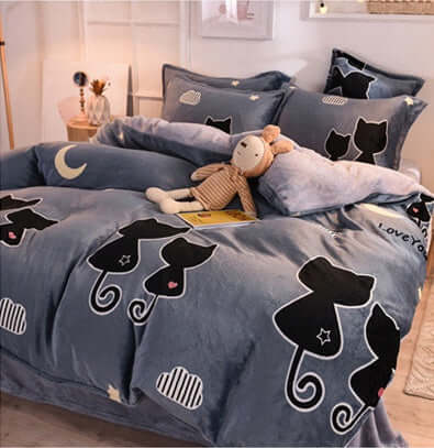 Cozy bed with cat-themed fleece duvet cover and pillows, perfect for winter comfort and warmth.