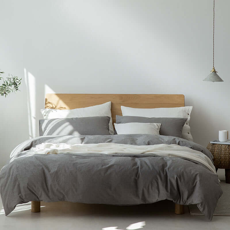 Japanese style Muji-inspired bed with gray and white bedding, perfect for modern minimalist decor.