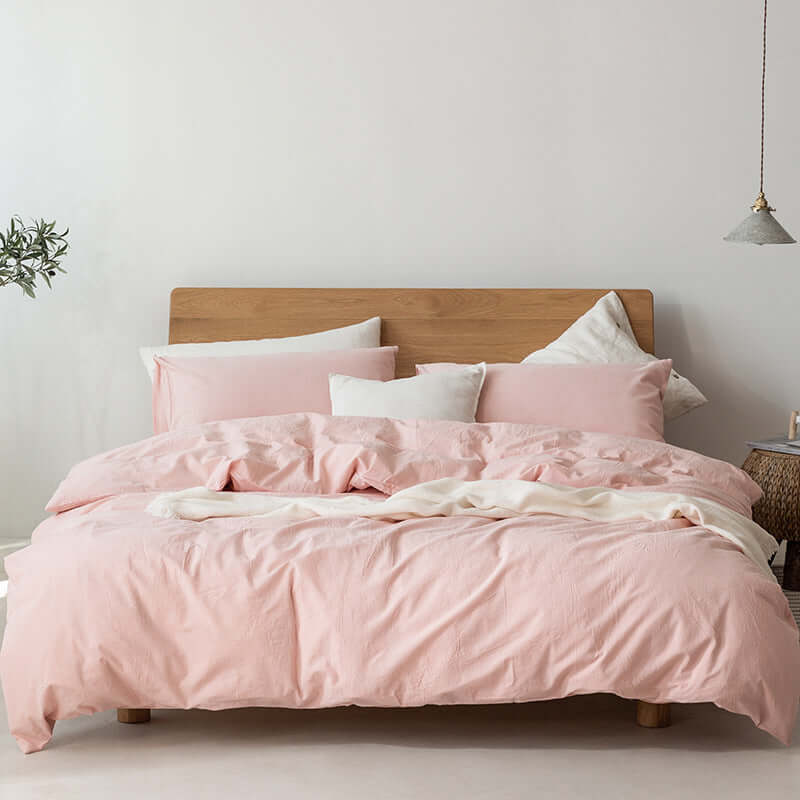 Japanese style Muji-style pink duvet cover and bed sheets on a wooden bed in a modern bedroom setting.