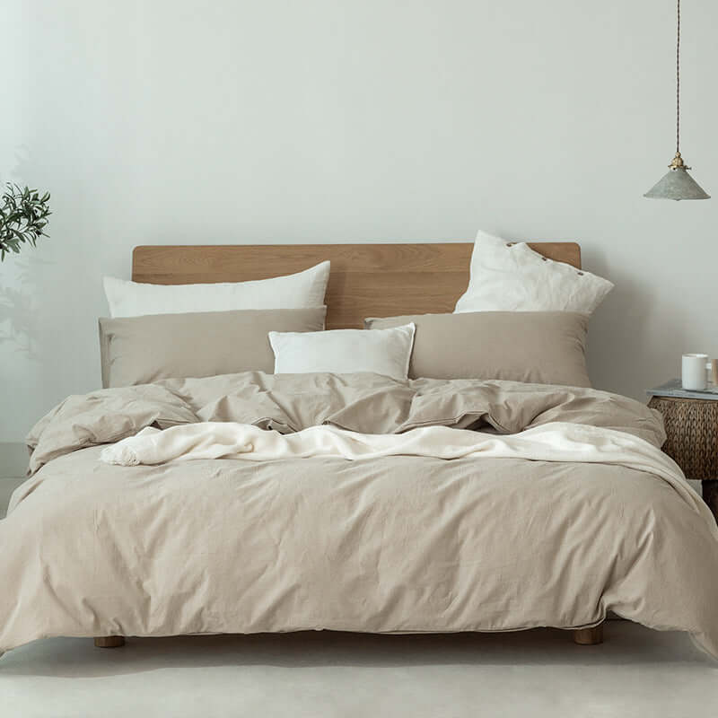 Japanese style Muji-style bedding set with neutral tones, featuring duvet cover and pillows on a wooden bed.