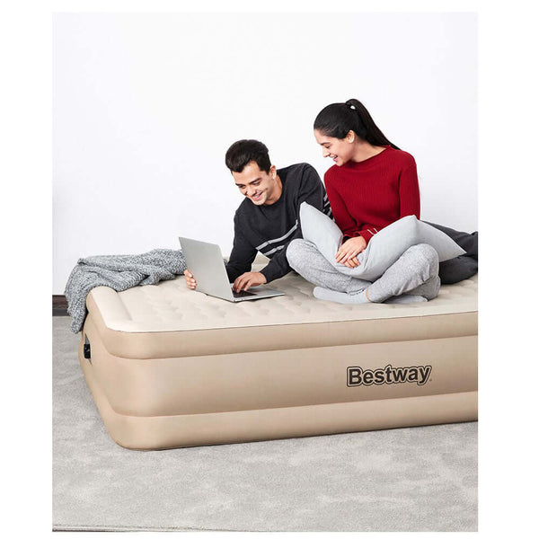 Couple enjoying time on a Bestway inflatable air mattress while using a laptop.