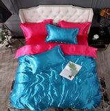 Vibrant pink and blue silk bed sheet quilt cover set with pillows arranged elegantly on a stylish bed.