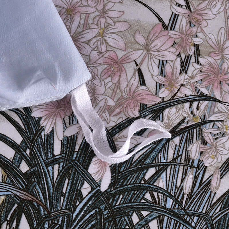 Close-up of fashionable high-end satin duvet cover with pastel plant printing and fabric ties.