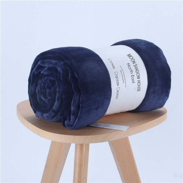 Navy blue flannel coral fleece blanket rolled on a wooden stool, perfect for air-conditioning and cozy naps.