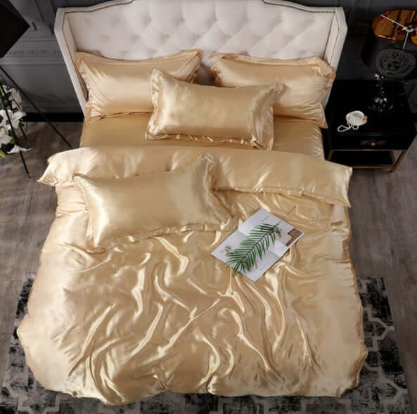Elegant gold silk bed sheet quilt cover set with decorative pillows on a stylish bed.