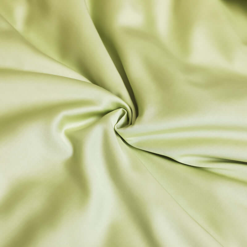Close-up of soft, washed ice silk fabric in a light green color, perfect for sleeping and bedding.