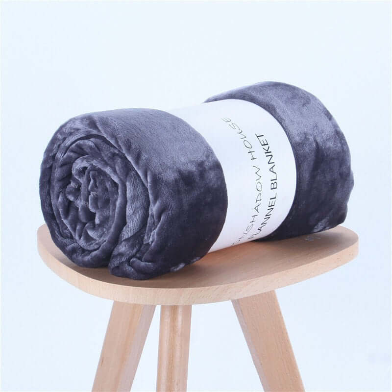 Rolled dark gray flannel nap blanket displayed on a wooden stool, perfect for air-conditioning comfort.