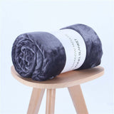 Rolled dark gray flannel nap blanket displayed on a wooden stool, perfect for air-conditioning comfort.