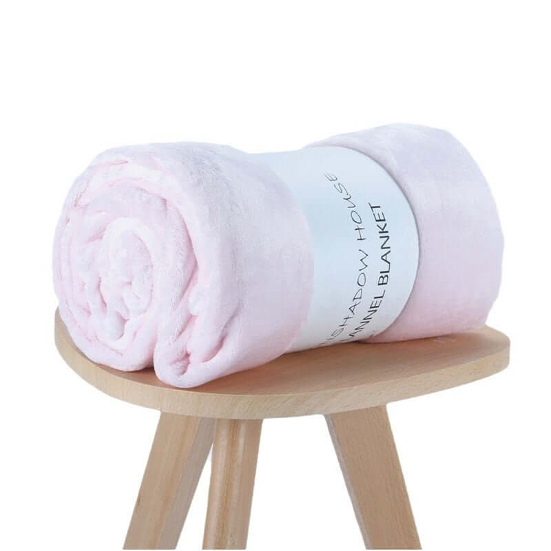 Rolled pink flannel blanket on a wooden stool, showcasing soft texture and cozy design, perfect for air-conditioning use.
