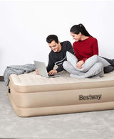 Couple enjoying relaxation on a Bestway single double layer inflatable bed with laptop and pillows.