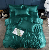 Elegant teal silk bed sheet quilt cover set with multiple pillows for a luxurious sleep experience.
