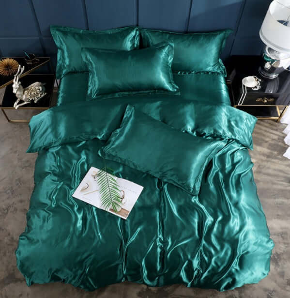 Elegant teal silk bed sheet quilt cover set with multiple pillows for a luxurious sleep experience.