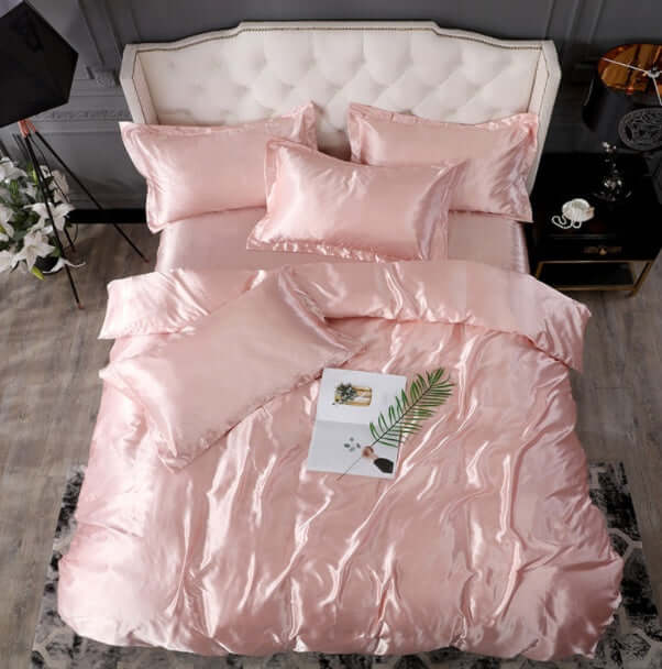 Pink silk bed sheet quilt cover set with decorative pillows for a luxurious sleep experience.